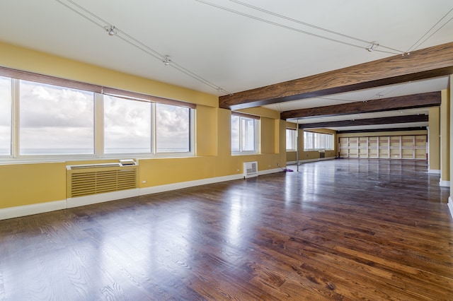 spare room featuring a wall mounted AC, a wealth of natural light, beam ceiling, and dark hardwood / wood-style flooring