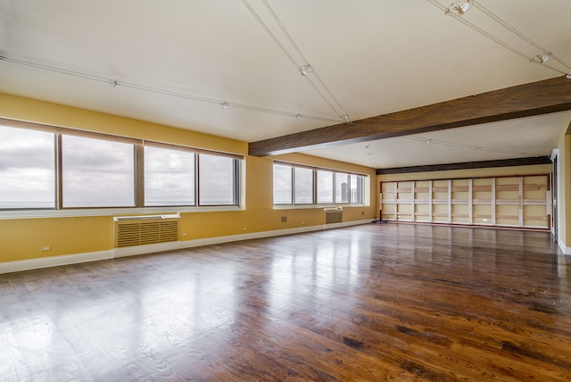 empty room featuring vaulted ceiling with beams, a wall unit AC, and hardwood / wood-style flooring