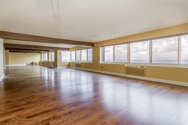 spare room with beamed ceiling, hardwood / wood-style flooring, and a wall mounted air conditioner