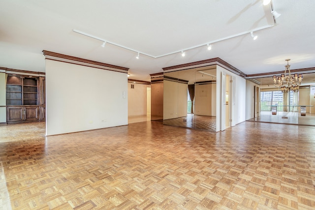 unfurnished room featuring light parquet flooring, rail lighting, ornamental molding, and a notable chandelier