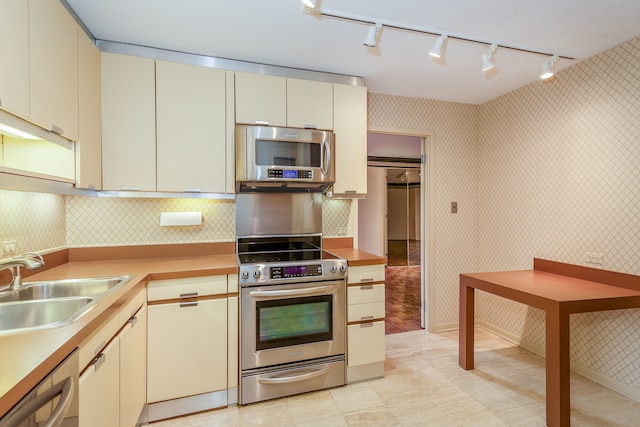 kitchen featuring cream cabinetry, sink, stainless steel appliances, and rail lighting