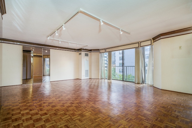 empty room with a textured ceiling, dark parquet flooring, and rail lighting