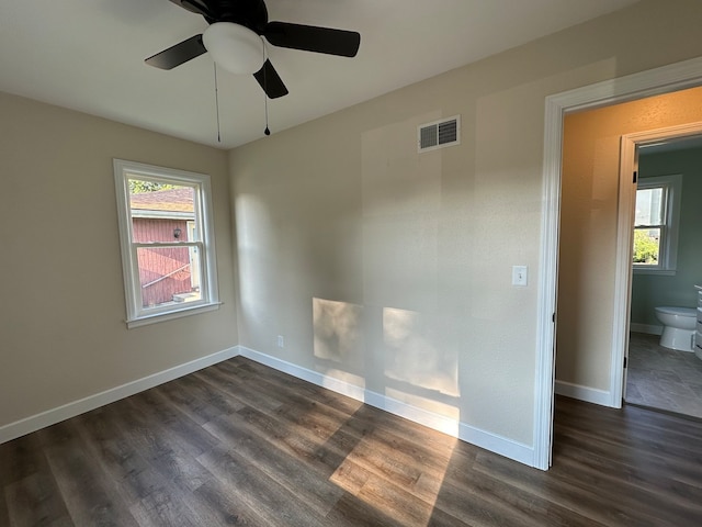 empty room with a wealth of natural light, ceiling fan, and dark hardwood / wood-style flooring