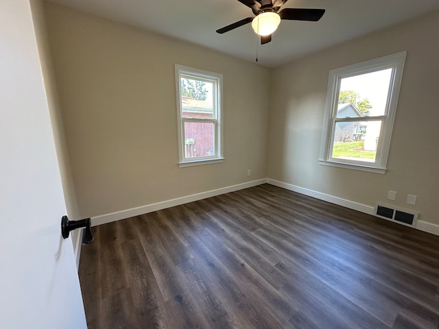 spare room with ceiling fan, a wealth of natural light, and dark hardwood / wood-style flooring