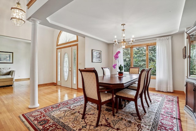 dining room with decorative columns, a notable chandelier, and light hardwood / wood-style floors