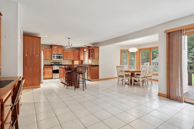 kitchen with appliances with stainless steel finishes, decorative light fixtures, a kitchen bar, and light tile patterned flooring