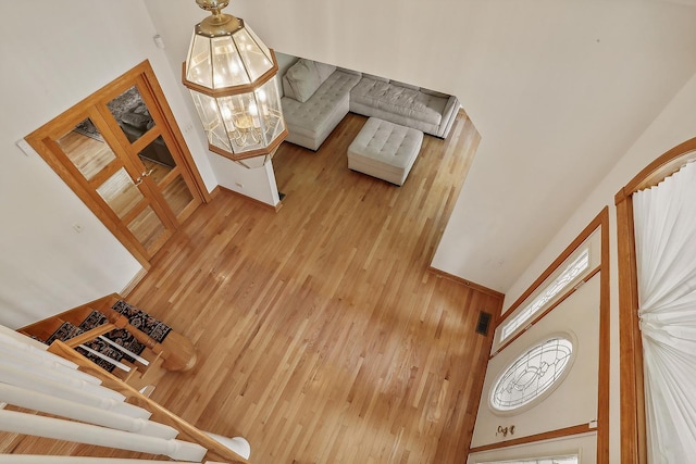 living room featuring a towering ceiling, wood walls, and a chandelier