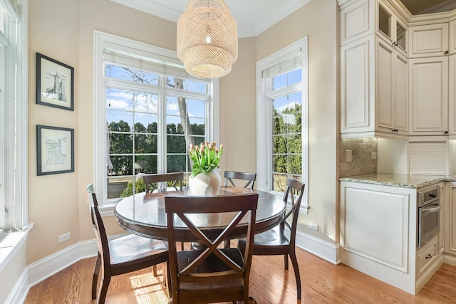 dining space with crown molding, a notable chandelier, baseboards, and light wood-type flooring