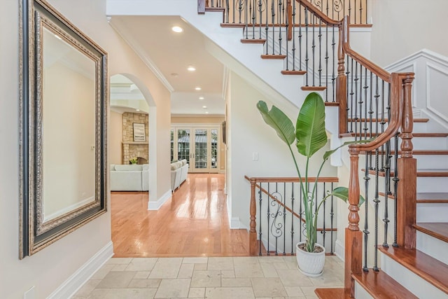 entryway featuring baseboards, ornamental molding, stone tile floors, recessed lighting, and arched walkways