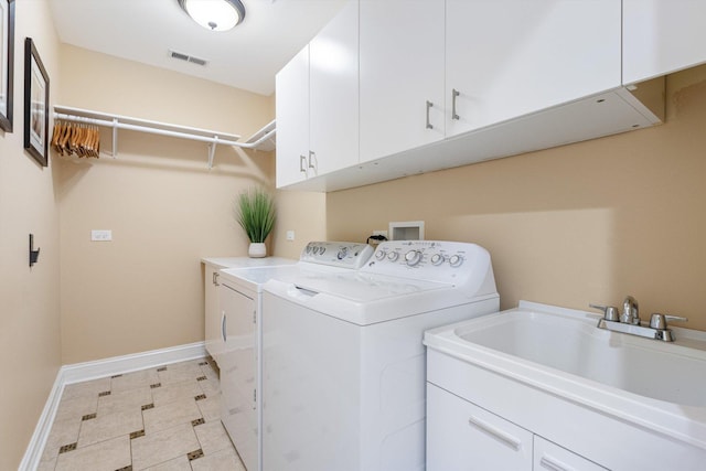 clothes washing area featuring visible vents, a sink, cabinet space, baseboards, and washing machine and clothes dryer