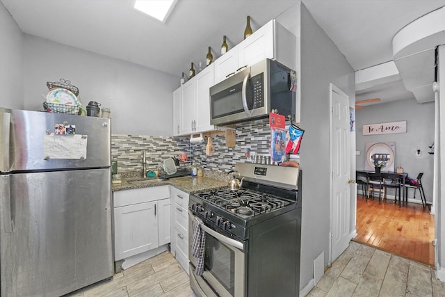 kitchen featuring light wood-type flooring, backsplash, white cabinetry, and stainless steel appliances