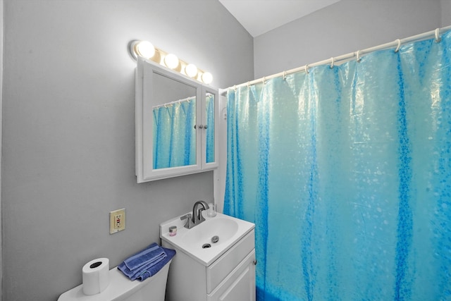 bathroom featuring toilet, vanity, and curtained shower