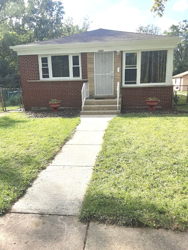 view of front of home with entry steps, brick siding, and a front lawn