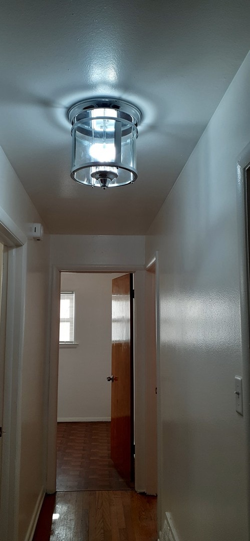 corridor with a chandelier and wood finished floors