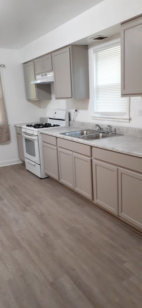 kitchen with light hardwood / wood-style floors, gas range gas stove, and gray cabinetry