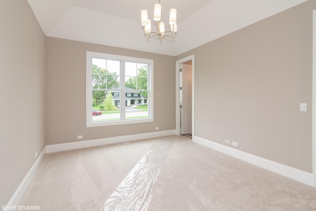 carpeted spare room with a chandelier and vaulted ceiling