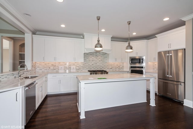 kitchen featuring a center island, decorative light fixtures, white cabinetry, stainless steel appliances, and sink