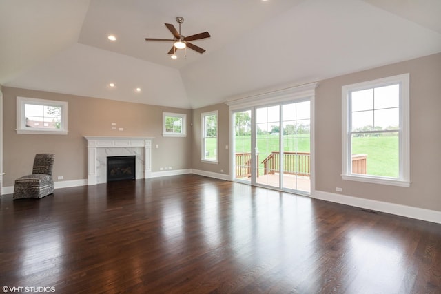 unfurnished living room with dark wood-type flooring, ceiling fan, a high end fireplace, and a healthy amount of sunlight