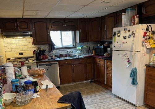 kitchen with appliances with stainless steel finishes, dark brown cabinets, a drop ceiling, and sink