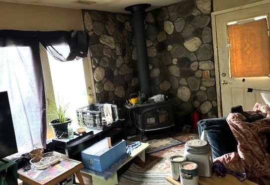 living room with wood-type flooring, a wood stove, and plenty of natural light