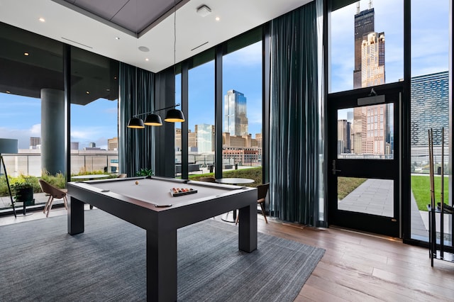 recreation room featuring floor to ceiling windows, pool table, hardwood / wood-style flooring, and a healthy amount of sunlight