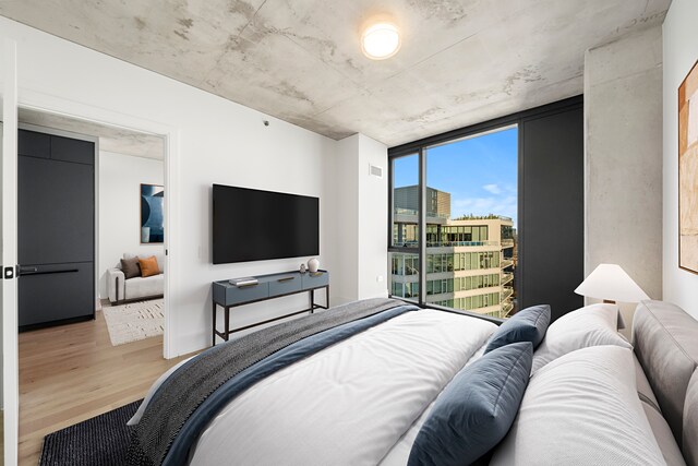 bedroom with expansive windows and hardwood / wood-style floors