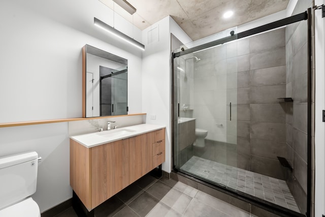 bathroom with vanity, toilet, tile patterned floors, and a shower with shower door