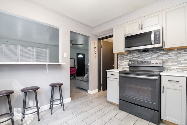 kitchen featuring black range with electric stovetop, ceiling fan, tasteful backsplash, white cabinetry, and light tile patterned floors