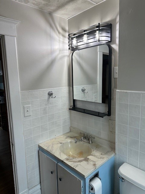 bathroom featuring vanity, tasteful backsplash, a textured ceiling, tile walls, and toilet