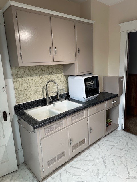 kitchen featuring light tile patterned flooring, sink, decorative backsplash, and gray cabinetry