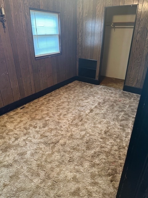 unfurnished bedroom with carpet and wooden walls