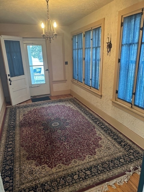 entryway with a textured ceiling, hardwood / wood-style floors, and a chandelier