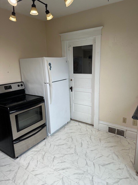 kitchen featuring light tile patterned flooring, electric range, and hanging light fixtures