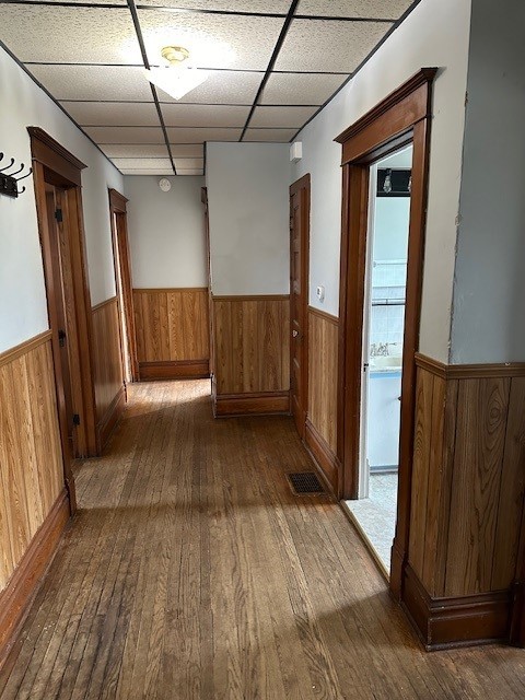 corridor with a drop ceiling and hardwood / wood-style flooring