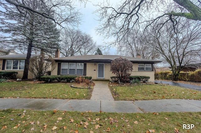 single story home with driveway, a front lawn, a chimney, and brick siding