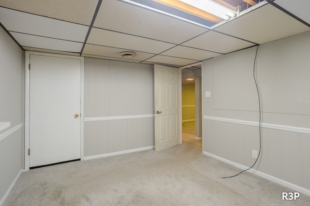 basement featuring a drop ceiling and light colored carpet