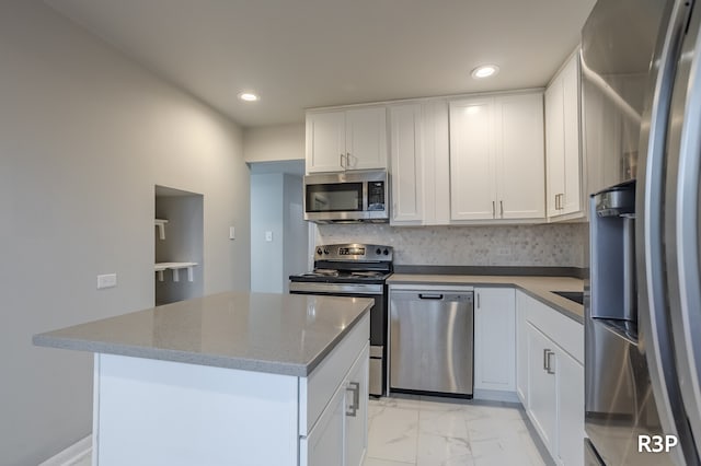 kitchen with stainless steel appliances, a kitchen island, and white cabinets