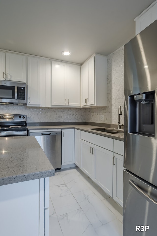 kitchen featuring sink, light tile patterned floors, appliances with stainless steel finishes, light stone countertops, and white cabinetry