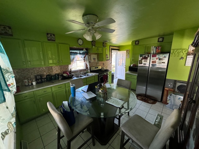 kitchen featuring ceiling fan, decorative backsplash, green cabinetry, light tile patterned flooring, and stainless steel appliances