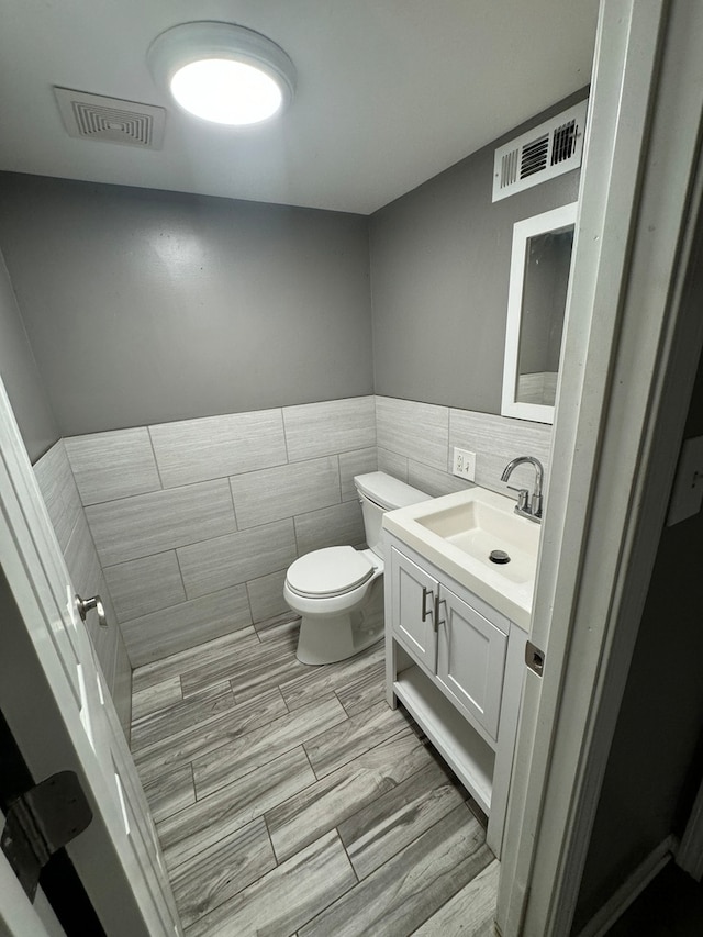 bathroom with decorative backsplash, vanity, tile patterned flooring, tile walls, and toilet