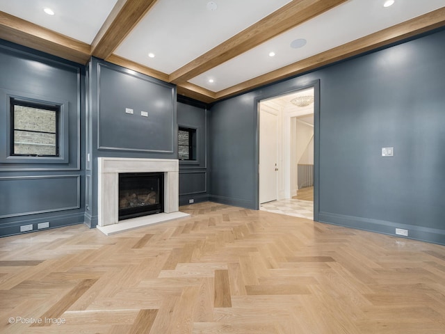 unfurnished living room featuring beamed ceiling, a high end fireplace, and light parquet floors