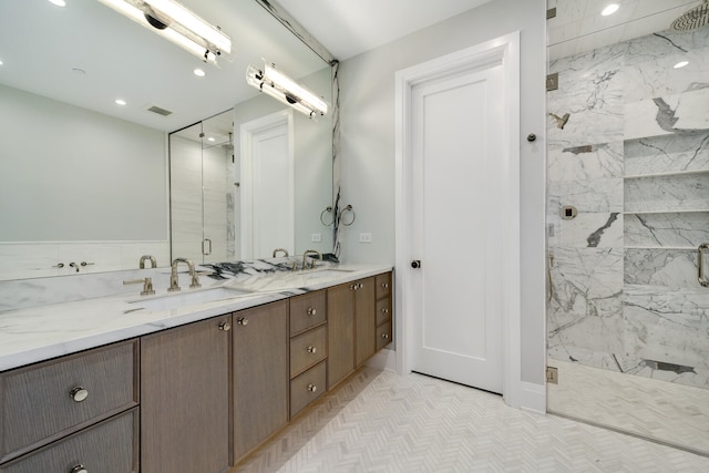 bathroom featuring dual bowl vanity, tile patterned flooring, and a tile shower