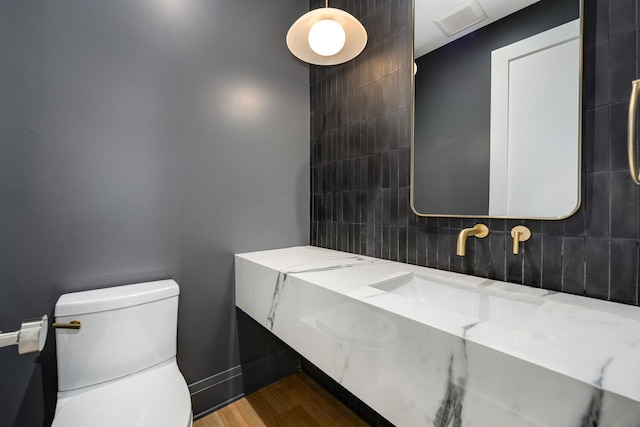 bathroom with tile walls, toilet, vanity, and wood-type flooring