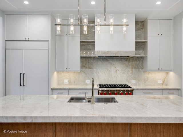 kitchen with sink, white cabinetry, paneled built in refrigerator, and backsplash