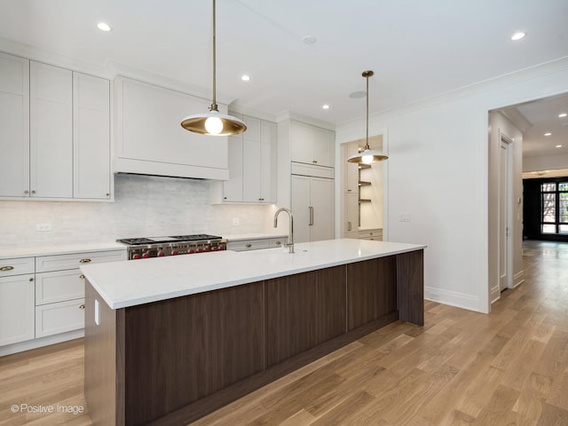 kitchen with light hardwood / wood-style floors, range, decorative backsplash, and decorative light fixtures