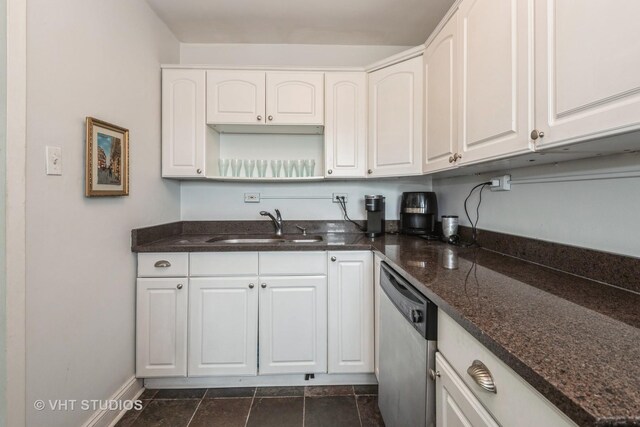 kitchen with dishwasher, white cabinetry, dark tile patterned flooring, sink, and dark stone counters