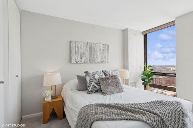 bedroom with a wall of windows, carpet flooring, and baseboards