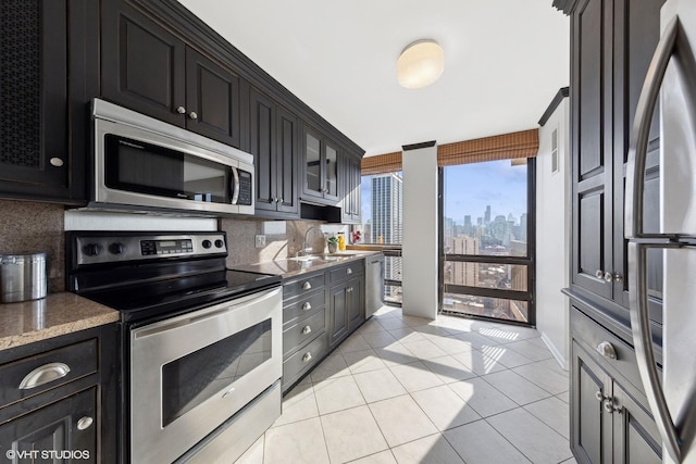 kitchen with light tile patterned floors, decorative backsplash, appliances with stainless steel finishes, and a view of city