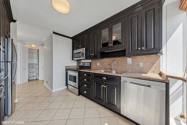 kitchen featuring tasteful backsplash, crown molding, light stone countertops, stainless steel appliances, and a sink