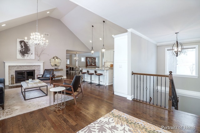 living room with a stone fireplace, high vaulted ceiling, an inviting chandelier, and dark hardwood / wood-style flooring